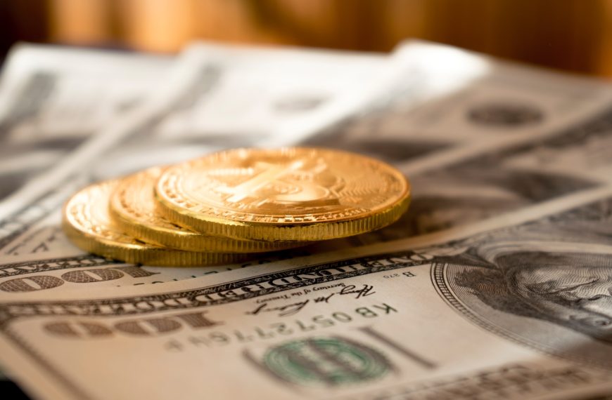 three round gold-colored coins on 100 US dollar banknotes